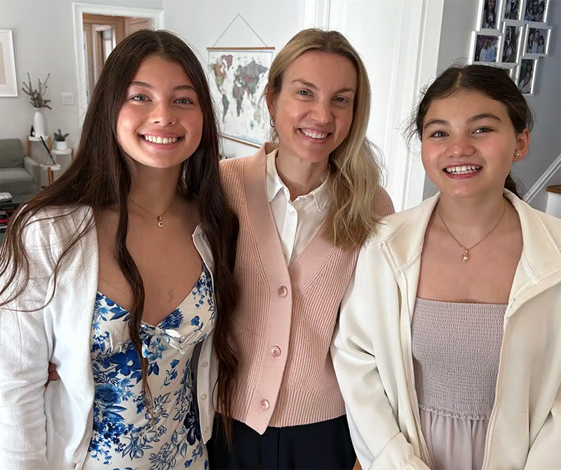 A woman and two teenage girls smiling indoors, family portrait, Ocean City Moms.