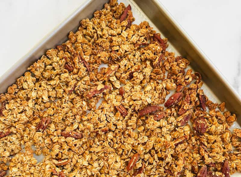 Oatmeal granola with nuts and dried fruit on baking sheet for healthy breakfast.