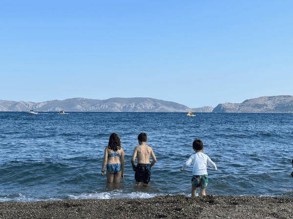 Three children playing in the ocean at Ocean City with mountains in the background.